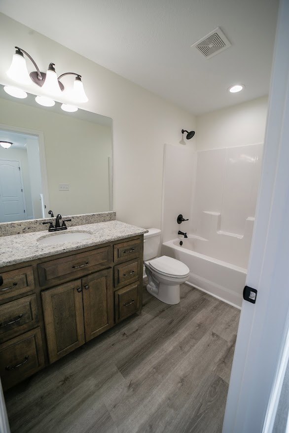 White bathroom with wall-mounted sink featuring a black faucet, modern toilet, light gray tile walls, and minimalist cabinetry