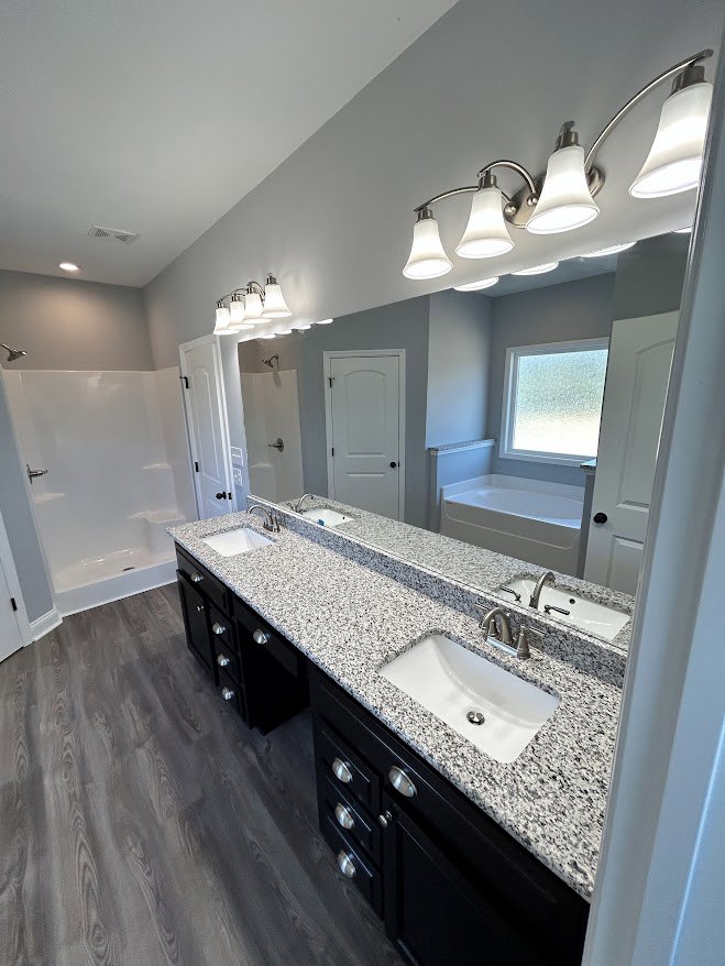 Marble countertop with double white sinks and chrome faucets, freestanding bathtub, frosted glass window, white door with black hardware, light tile flooring