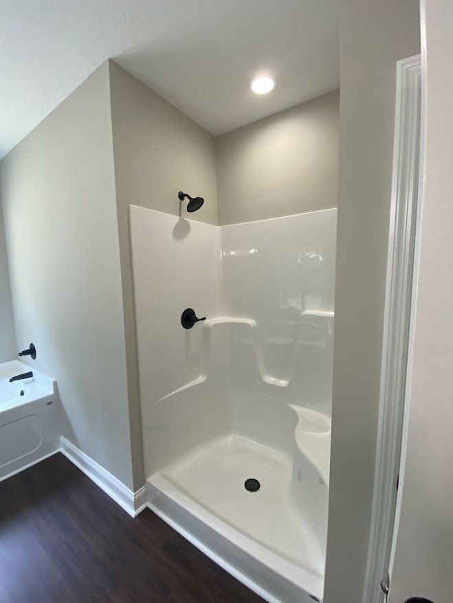 Glass-enclosed shower with white tile walls, chrome fixtures, and built-in niche in modern bathroom