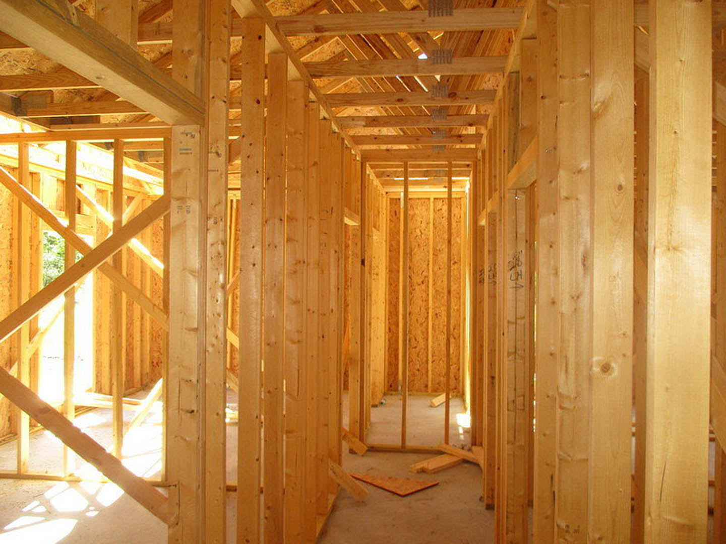 Exposed wooden beams and framing inside a residential home under construction, unfinished walls and ceiling visible
