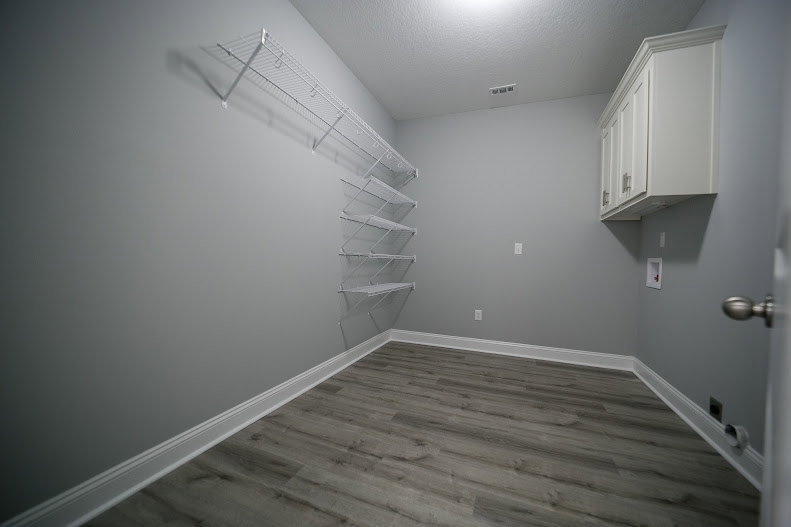 Wood floor with white baseboards, built-in shelves and cabinets along plaster walls, recessed ceiling lighting