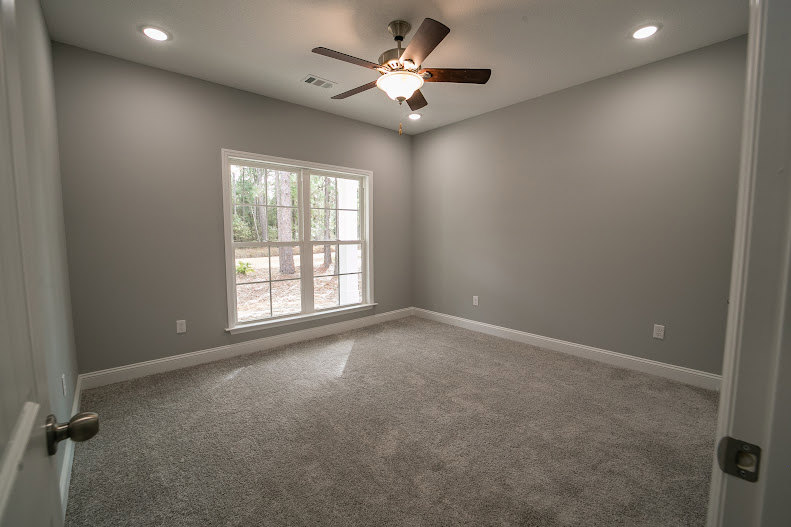 Neutral-toned room with plaster walls, wood flooring, ceiling fan, and single window letting in natural light