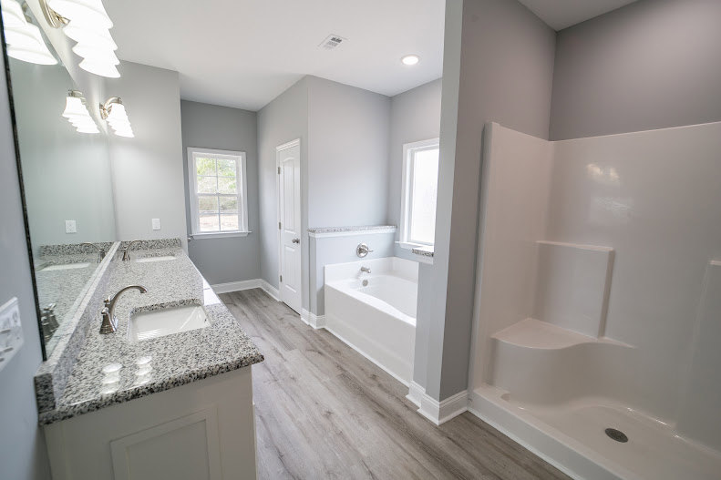 White freestanding bathtub with silver faucet beside rectangular sink, light gray tile walls, and chrome bathroom fixtures