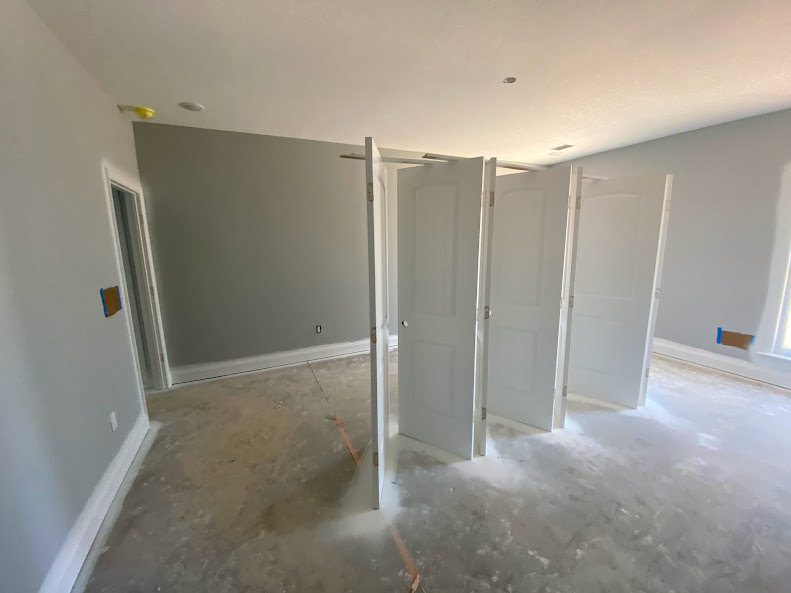 White paneled door with round silver knob set in matching white frame, surrounded by smooth plaster walls and light hardwood flooring
