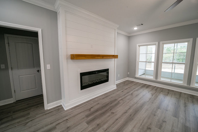 Living room with plaster walls, hardwood flooring, and a black and white stove fireplace