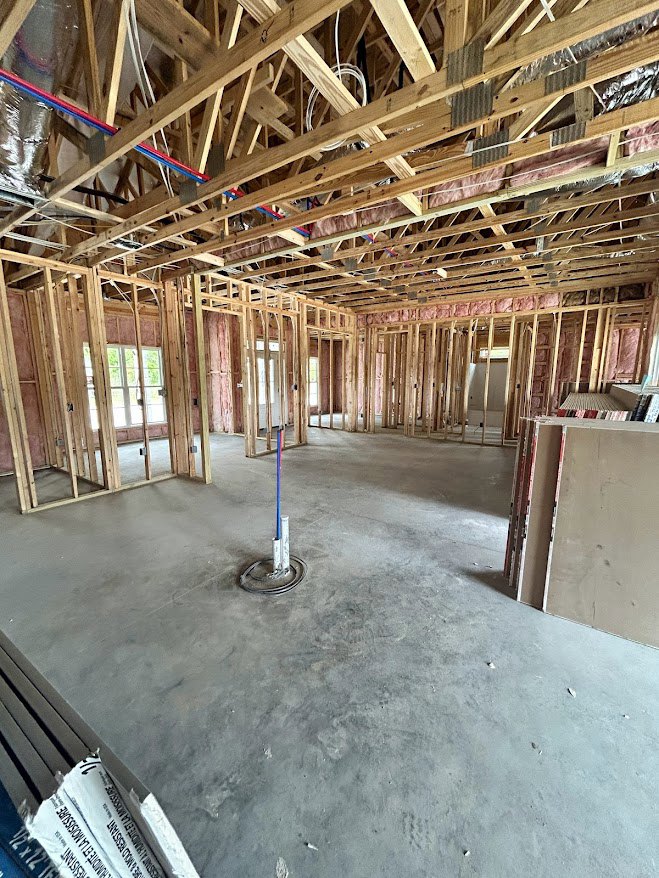 Unfinished room with exposed wooden framing, concrete floor, and central steel support pole