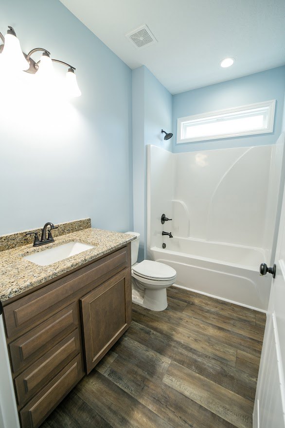 Modern bathroom with white porcelain sink, chrome faucet, and matching toilet; light gray tile flooring and wall, minimal decor