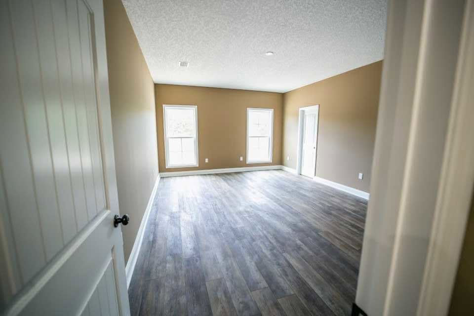 Wood floor room with two windows, white framed door, white ceiling, and ceiling light fixture