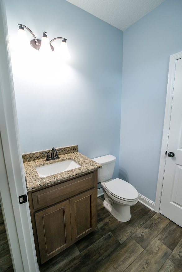 Bathroom with marble countertop sink, chrome faucet, white toilet, light tile flooring, and neutral wall tiles