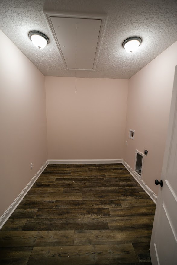 Wood floor room with white walls, modern ceiling light fixture, and white door with black knob