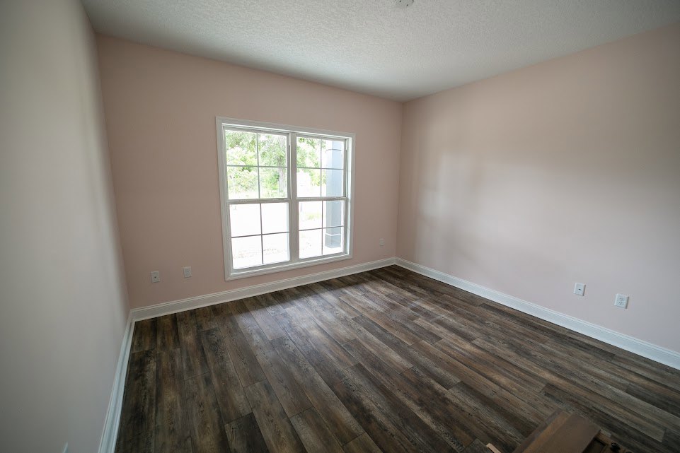 Sunlit room with multi-pane window, pink plaster walls, and hardwood floor