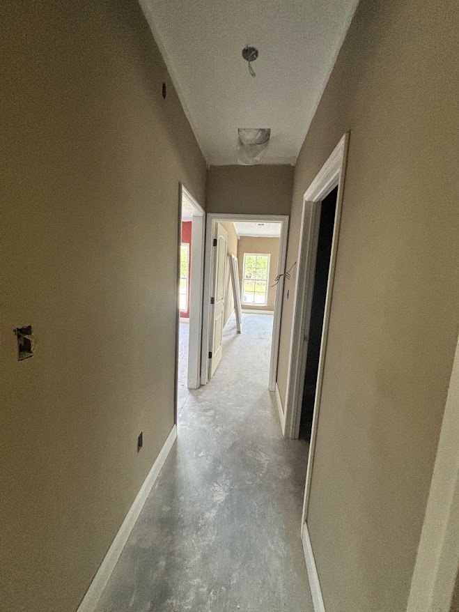 Hallway with plaster walls, composite flooring, white ceiling, wooden door, and rectangular window