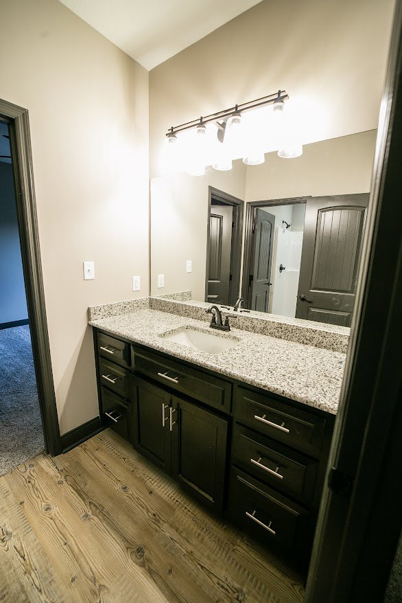 Bathroom featuring marble countertop, rectangular mirror, white cabinetry, chrome faucet, and tiled walls