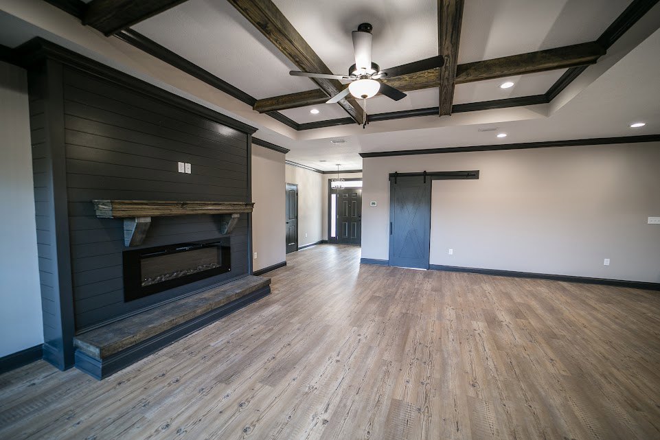 Living room with light wood flooring, white plaster walls, modern fireplace, and large sliding glass door.
