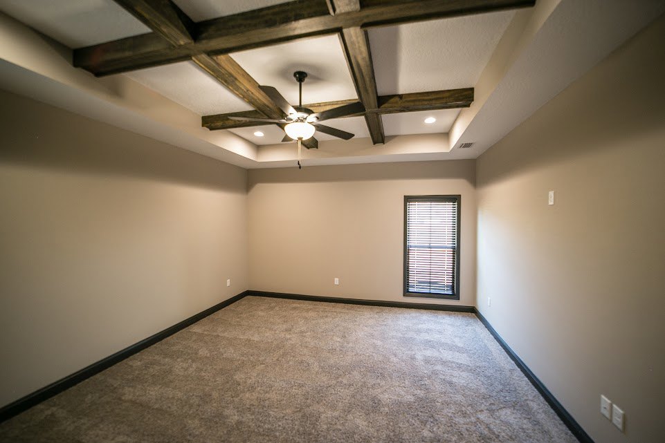 Carpeted bedroom with white walls, ceiling fan, and window with closed blinds