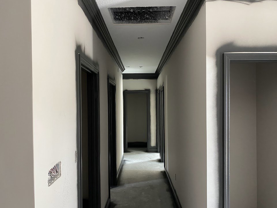 Hallway with white plaster walls, black trim, black door, and ceiling fixtures
