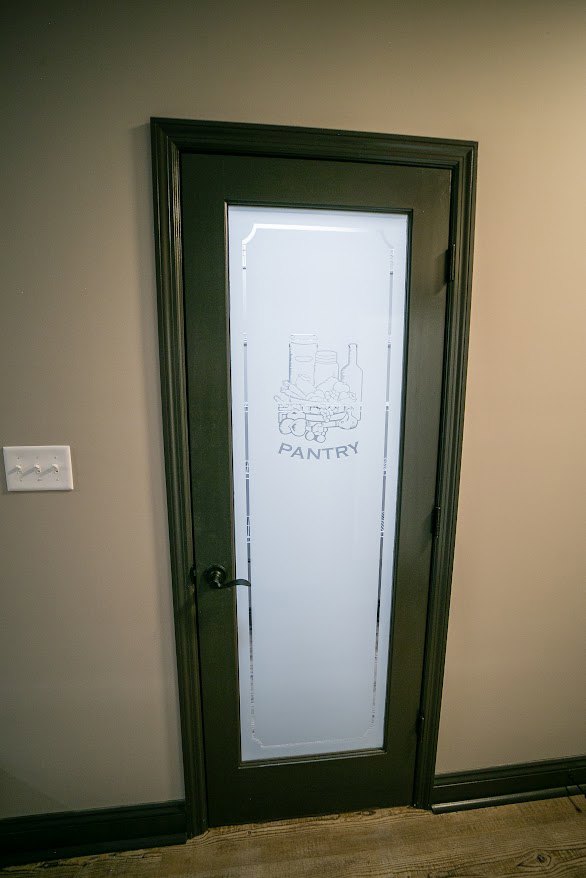 White interior door with frosted glass panel and silver handle, set against a light-colored wall