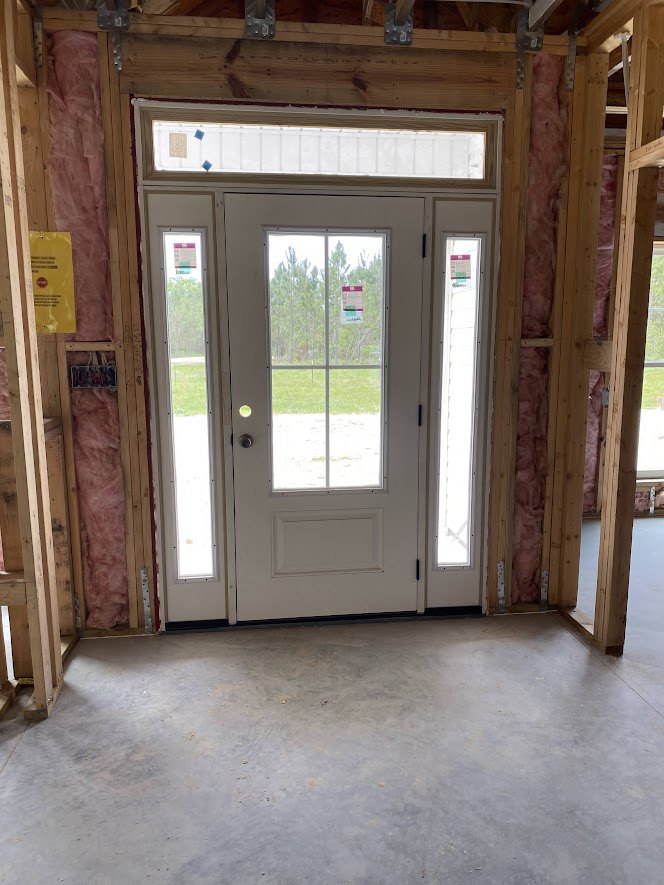 White door with glass panes set in a wood-framed room, concrete floor, yellow sign with black text on window