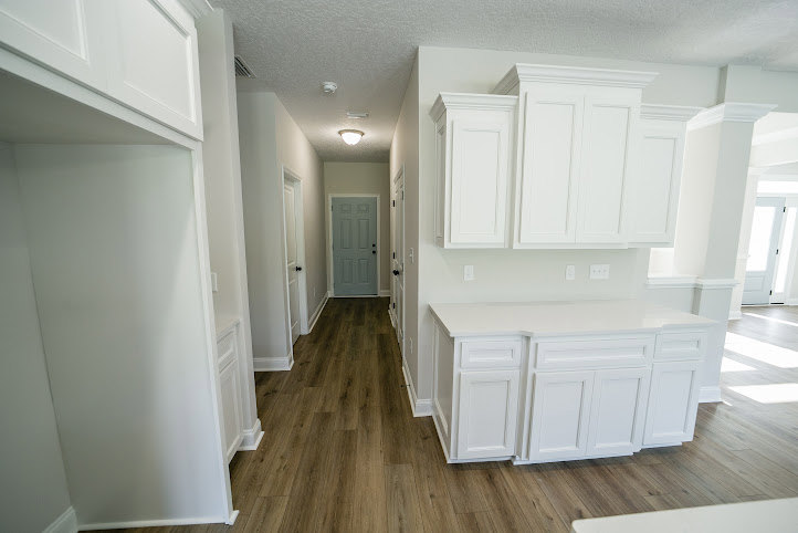 White kitchen featuring shaker cabinets, marble countertops, stainless steel appliances, and wide plank hardwood flooring