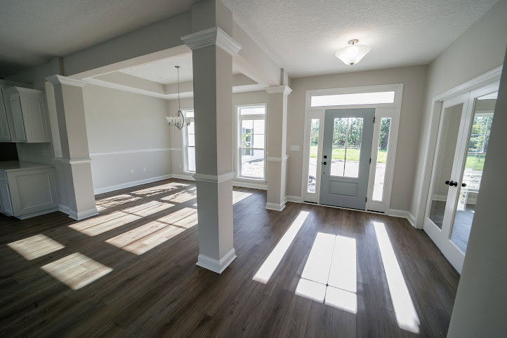 Room with light wood laminate flooring, white plaster walls, solid door, and adjacent glass door leading to another space