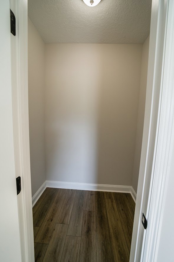 Wood flooring, white paneled door, smooth plaster walls, and ceiling in a bright residential interior.
