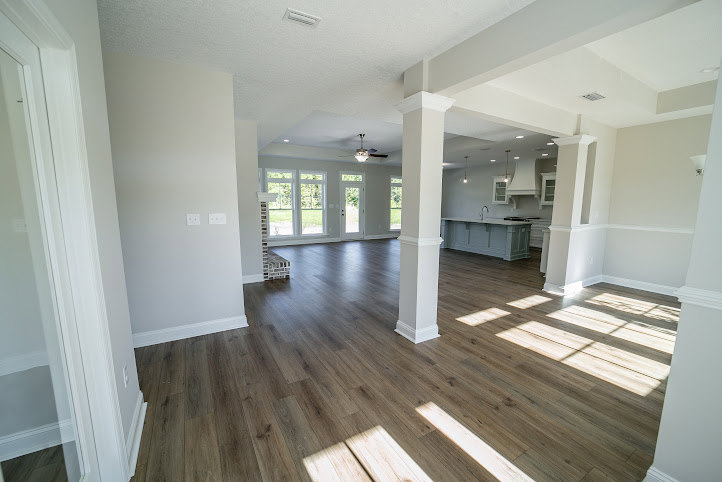 Wood flooring and white walls in a bright residential room with a smooth ceiling