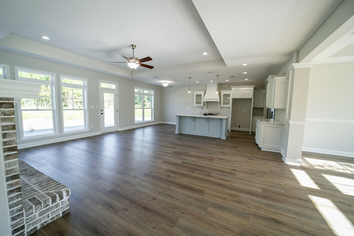 Spacious room featuring wood flooring, plaster walls, and a ceiling fan with light fixture