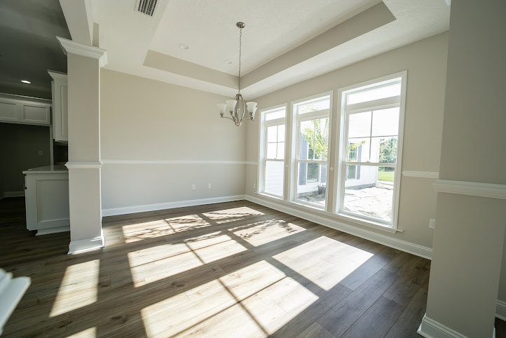 Wood flooring in a bright room with large windows, white walls, ceiling molding, and baseboards