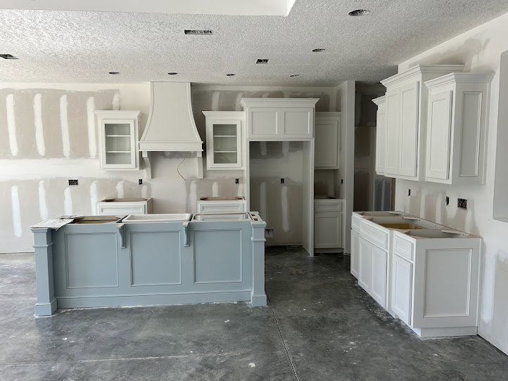 White kitchen cabinets with stainless steel hood, subway tile backsplash, stone countertops, and undermount sink.