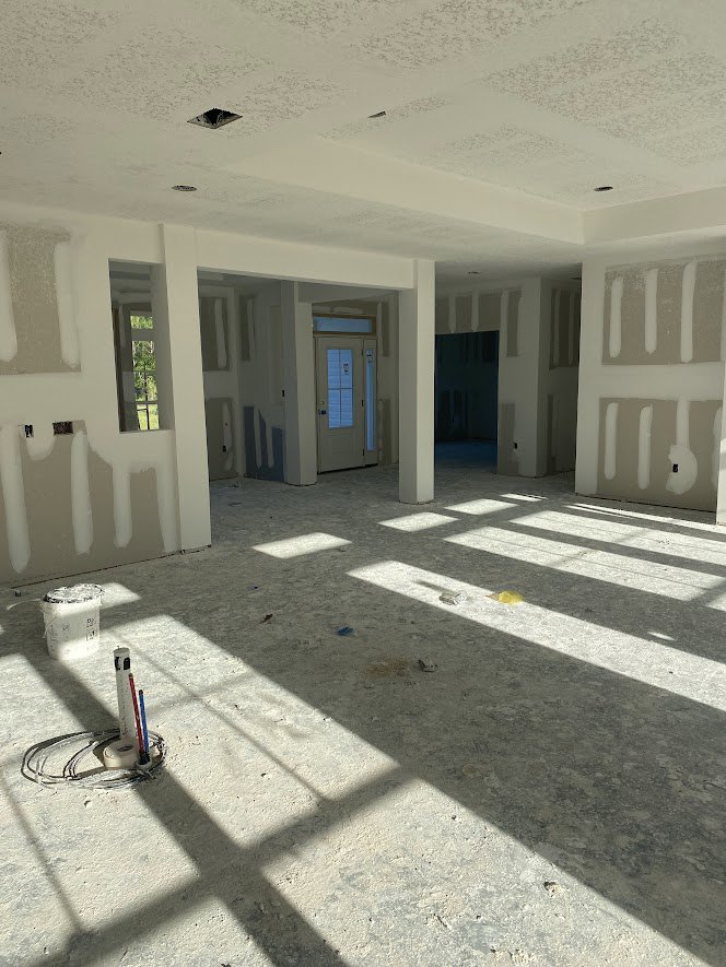 White-walled room with a white ceiling, light-colored flooring, and a door featuring a window panel