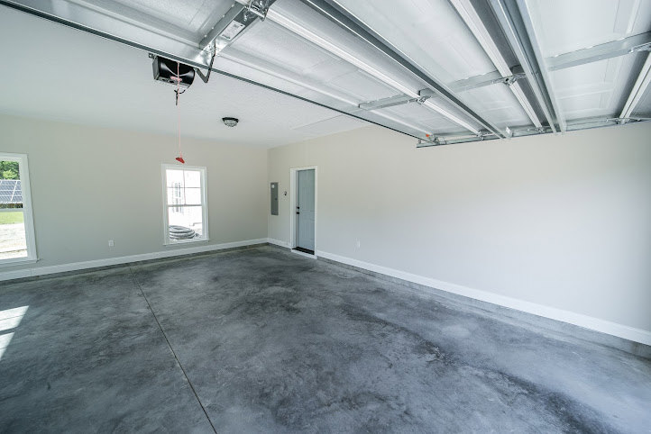 Concrete floor room with plaster walls, exposed ceiling beams, and natural daylighting