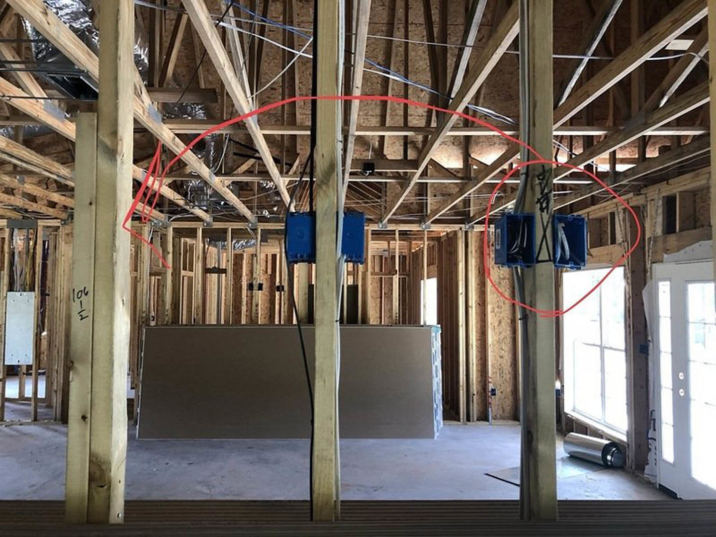 Unfinished interior with exposed ceiling beams, steel supports, insulation, and a red circle marked on the ceiling; white wall with black border, white door with window, and
