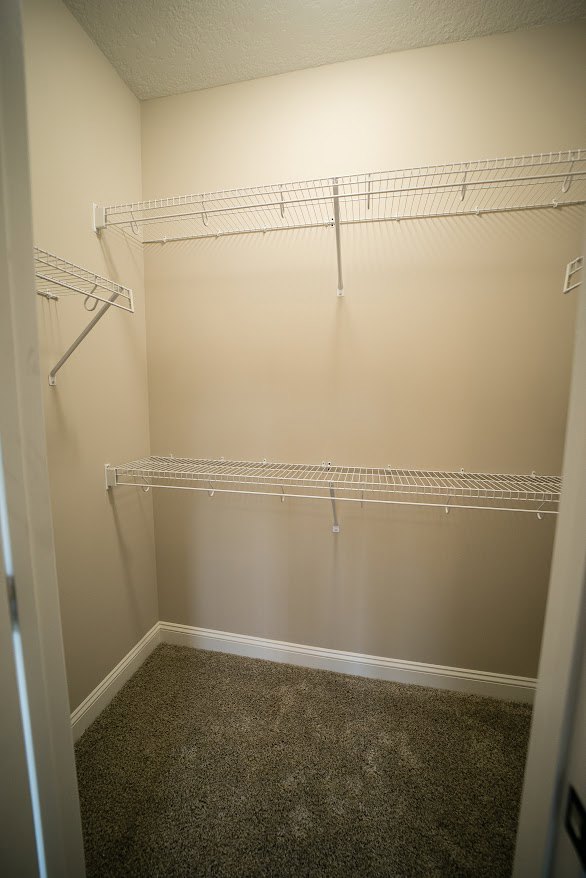 Walk-in closet with white wire shelving, beige carpet flooring, and smooth white walls