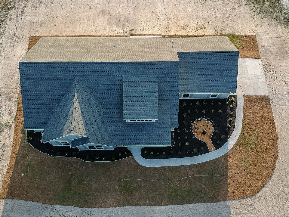 Modern home exterior with concrete driveway, manicured lawn, and light-colored siding