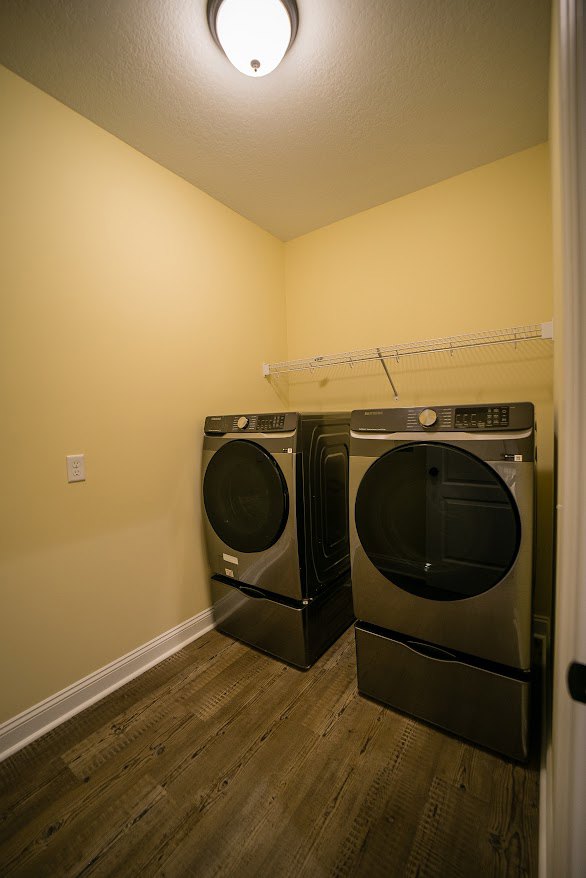 Front-loading washer and dryer set against white cabinetry in a laundry room with tile flooring and neutral walls