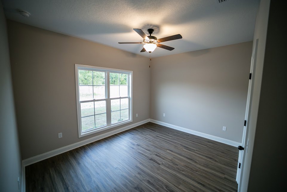 Wood flooring room with multi-pane window, plaster walls, and ceiling fan with illuminated light fixture
