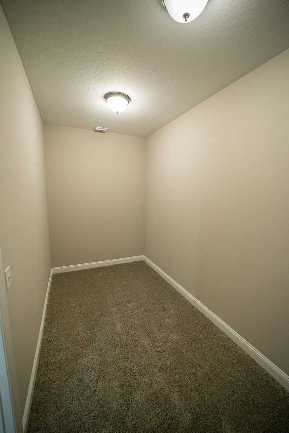 Spacious room with smooth plaster walls, light wood flooring, and a modern ceiling fixture illuminating the space