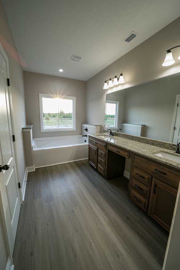 Bathroom featuring freestanding soaking tub, white vanity with undermount sink, stone countertop, tile flooring, and neutral wall finishes