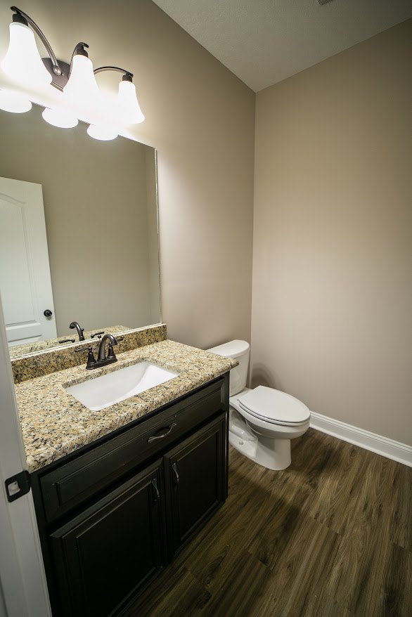 Marble countertop sink with chrome faucet, white toilet, light tile flooring, and neutral cabinetry in a modern bathroom