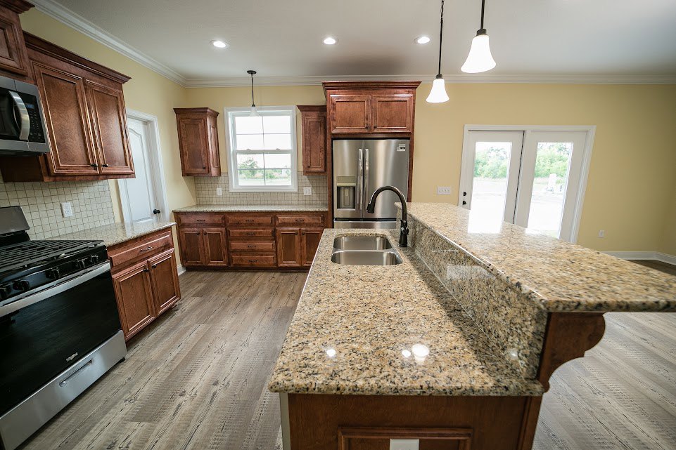 Granite countertops, stainless steel appliances, white cabinetry, hardwood flooring, double doors, window with natural light in a modern kitchen