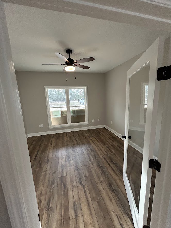 Ceiling fan with light fixture, wood flooring, large window overlooking yard, white walls with black hinge, wall-mounted mirror