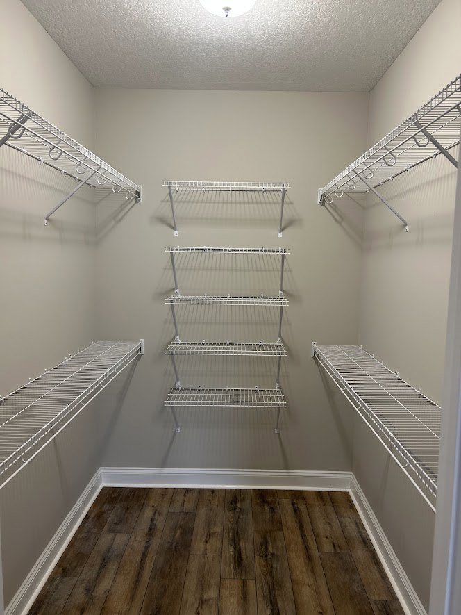 Closet with white wire shelves mounted on plaster walls, wood flooring, and white baseboards