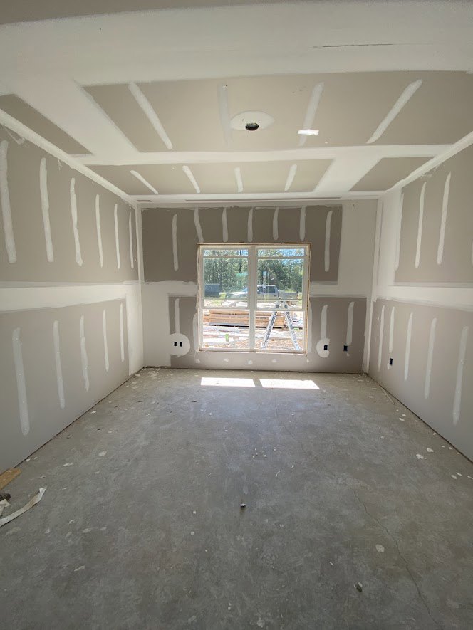 Room with white painted walls, white ceiling, window overlooking a truck and ladder outside, unfinished flooring