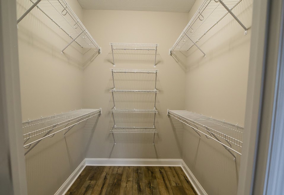 Closet with white wire shelving, white walls, and light wood flooring with white baseboards