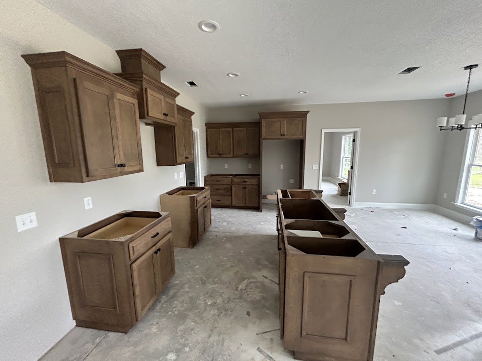 Kitchen with natural wood cabinets, built-in drawers, and open shelving, stainless steel sink, light-colored flooring, and neutral walls