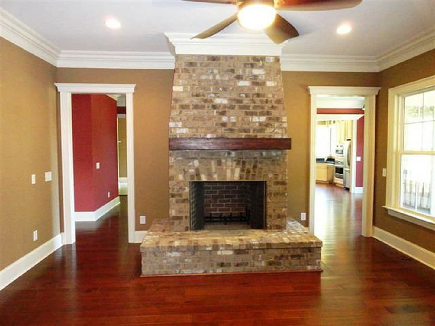 Brick fireplace with wood burning stove set against a red accent wall, white electrical outlet visible, stone hearth, close-up bench and window, bright overhead lighting, white