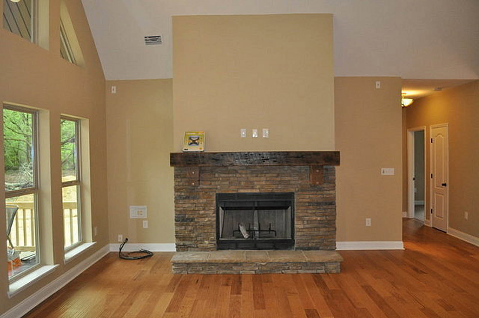 Stone fireplace with white decorative object on hearth, wood flooring, neutral walls, and modern interior design elements