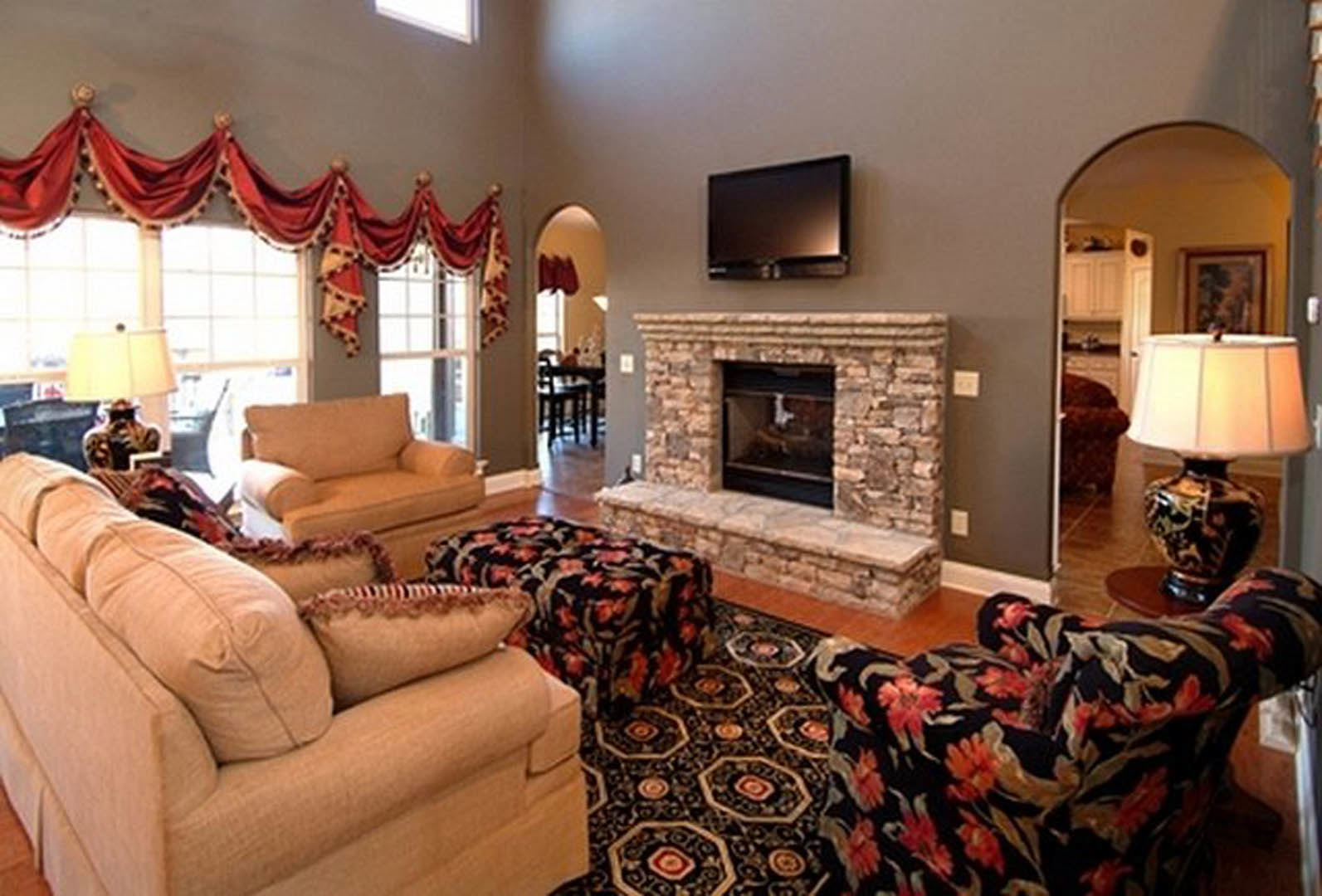 Living room with light-colored couches, decorative pillows, stone fireplace, hardwood floors, and neutral walls