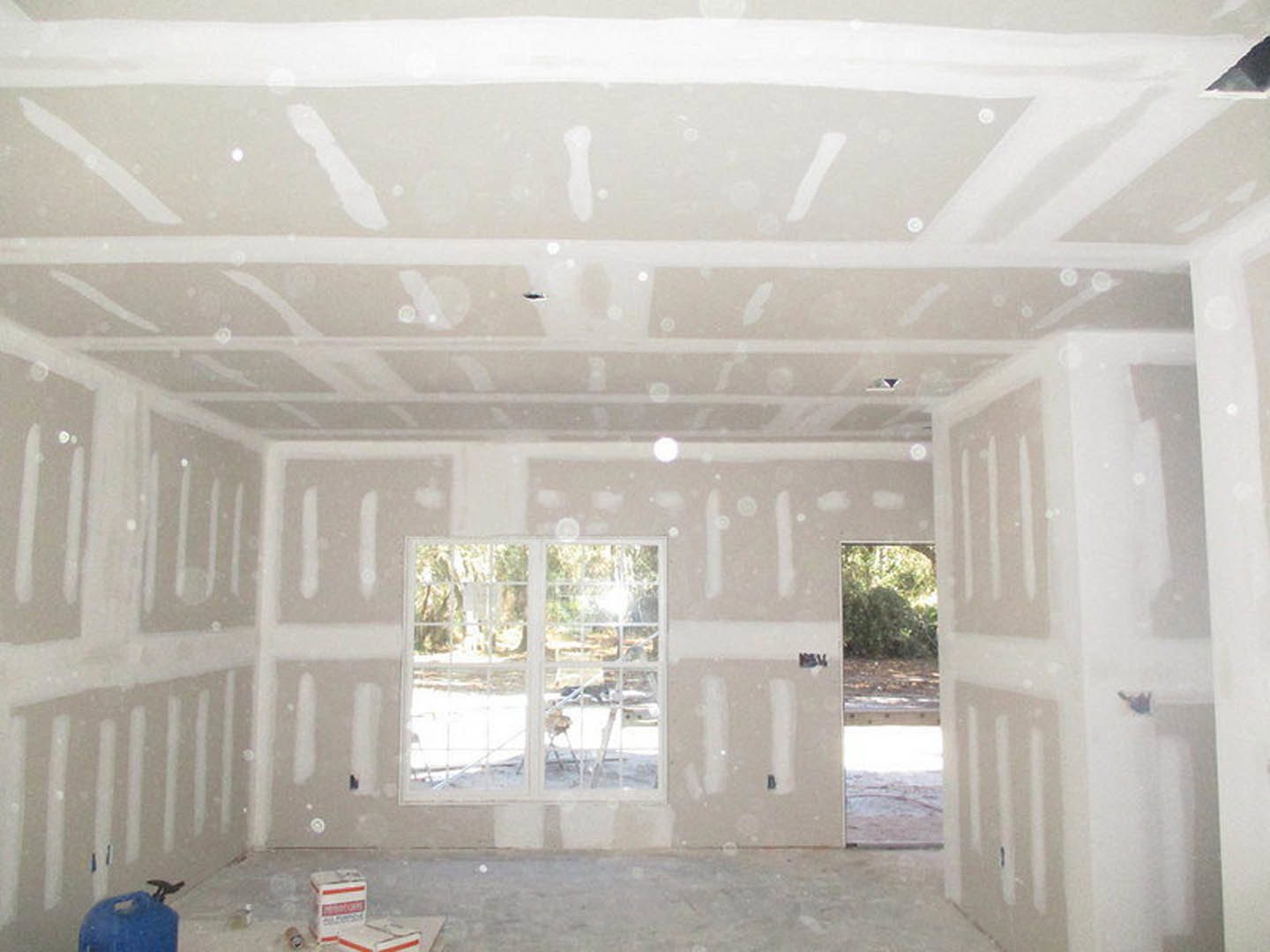 White-walled room with white ceiling, large window with white frame, blue plastic container on floor