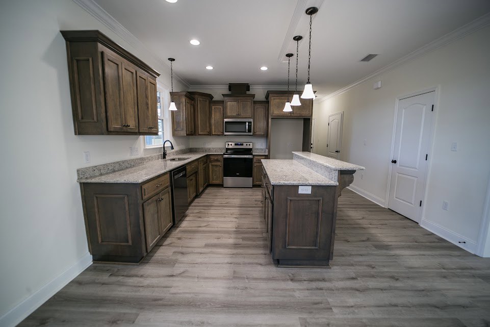 Kitchen with granite countertops, wood flooring, black and silver stove, white door with black handles, close-up of kitchen cabinets, ceiling chain fixture